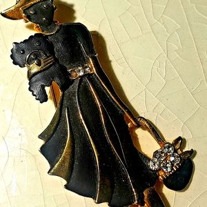 Vintage lady in black pleated dressed outlined in gold holding a puppy.